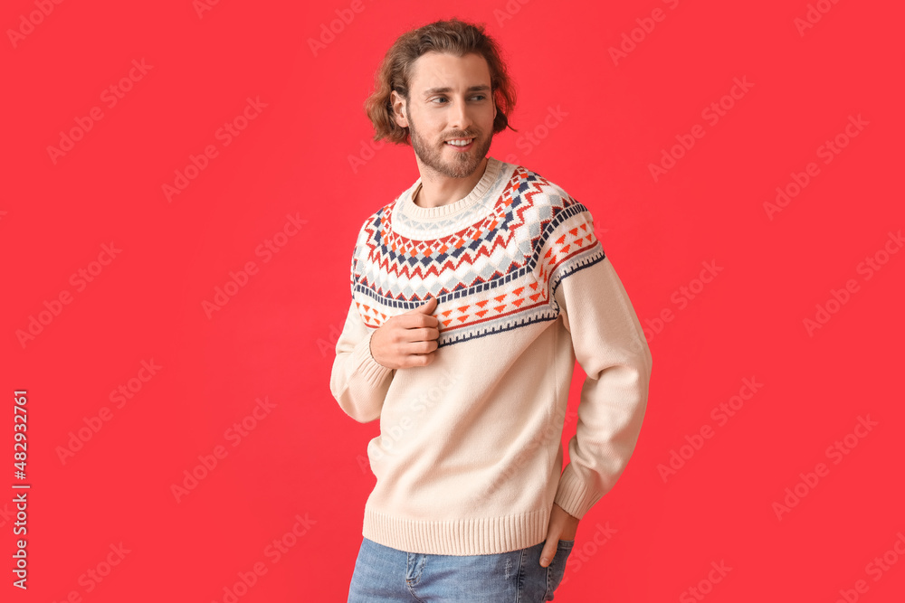 Handsome young man in knitted sweater on color background