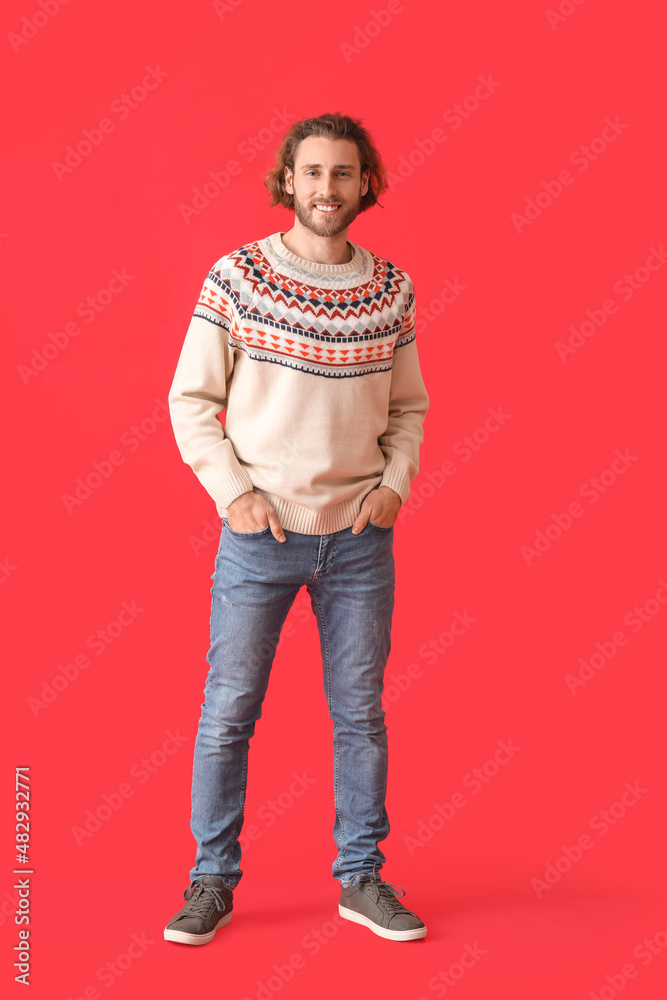 Handsome young man in knitted sweater on color background