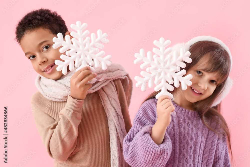 Cute little children in winter sweaters and with snowflakes on color background