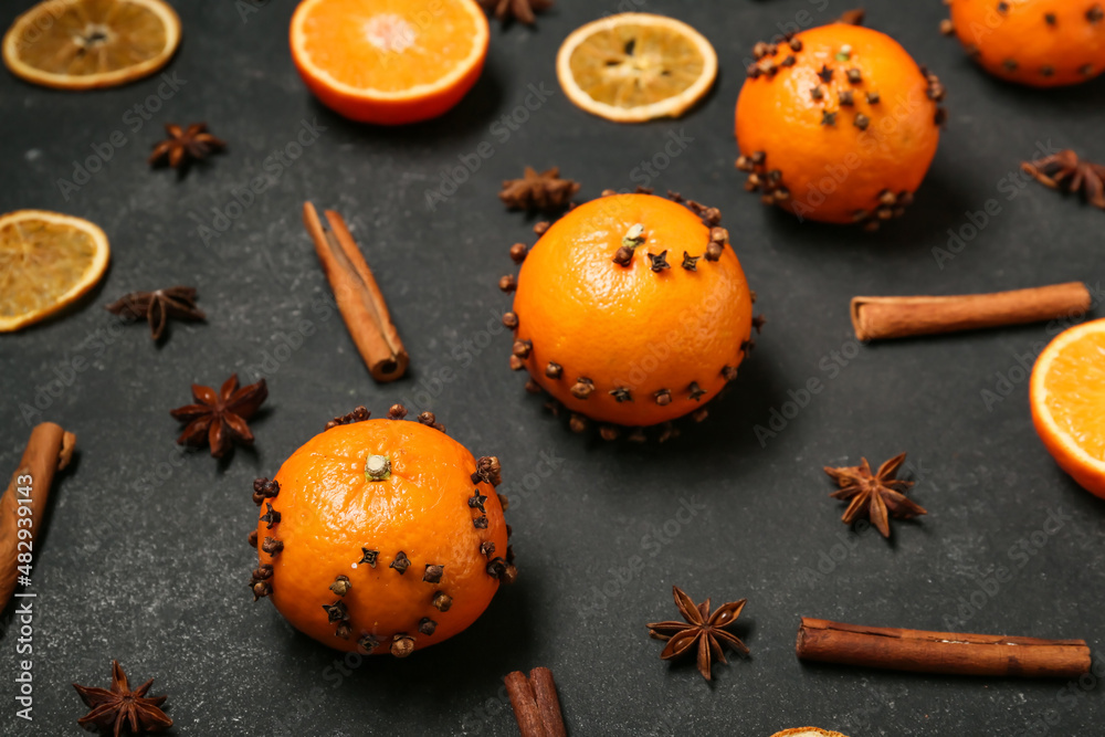 Handmade Christmas decoration made of tangerines with cloves on dark background, closeup