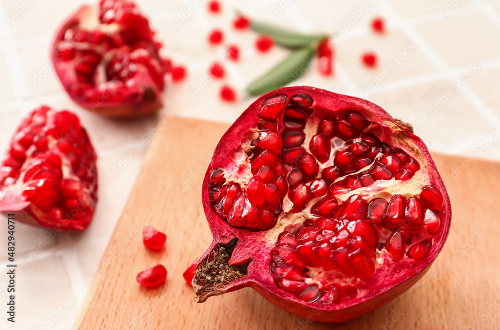 Ripe delicious pomegranate on light tile background