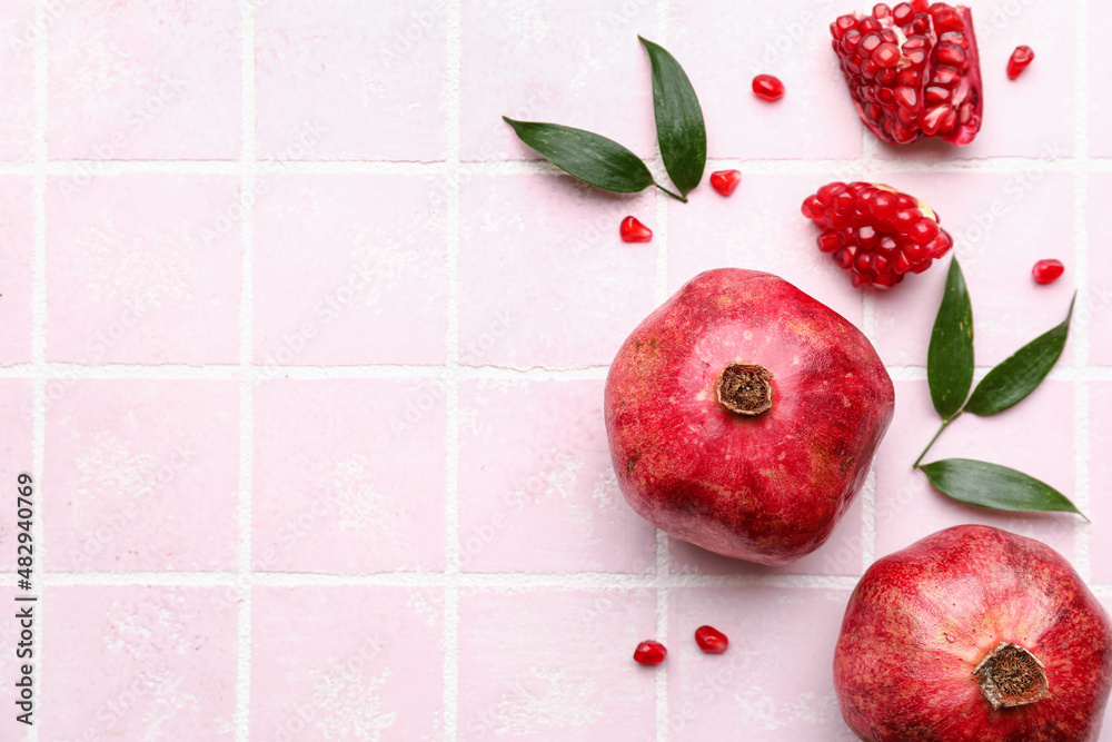 Delicious pomegranates on pink tile background