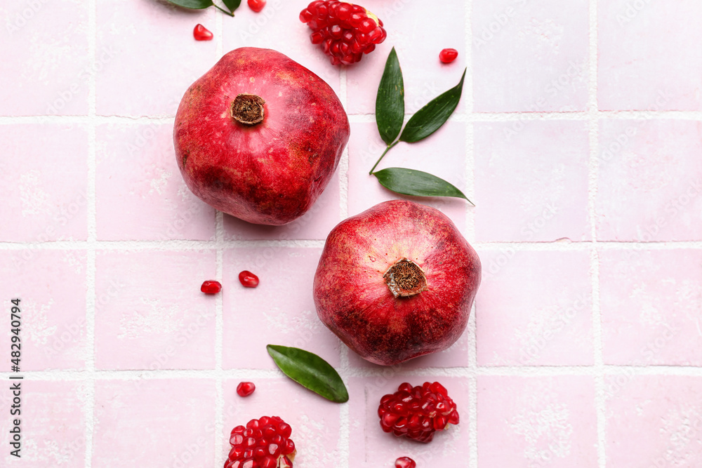 Delicious pomegranates on pink tile background