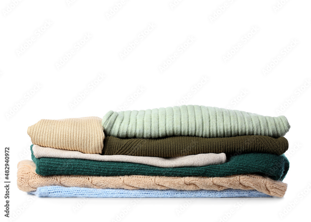 Stack of different knitted sweaters on white background