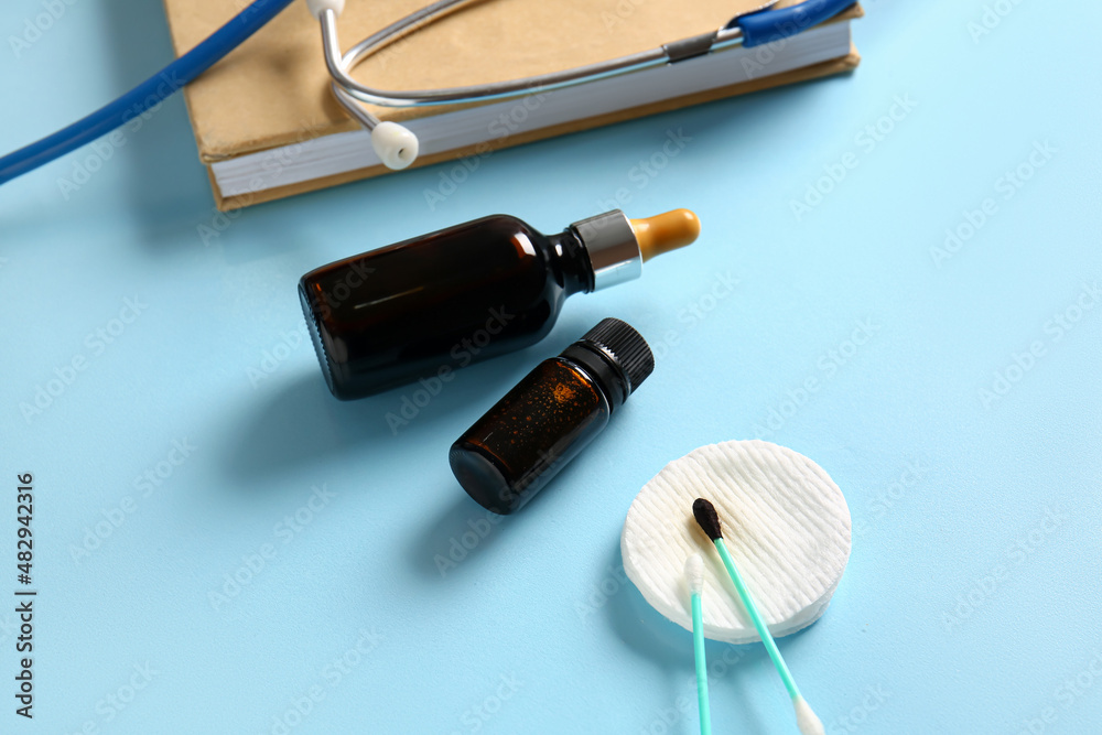 Bottles with iodine, cotton swab and pad on blue background, closeup