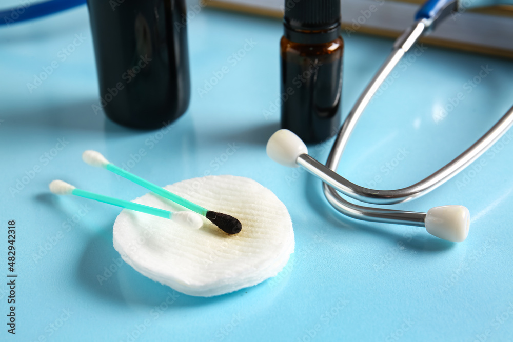 Cotton pad, swabs and stethoscope on blue table, closeup