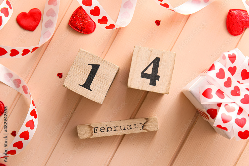 Calendar with date of Valentines Day and gift box on wooden background