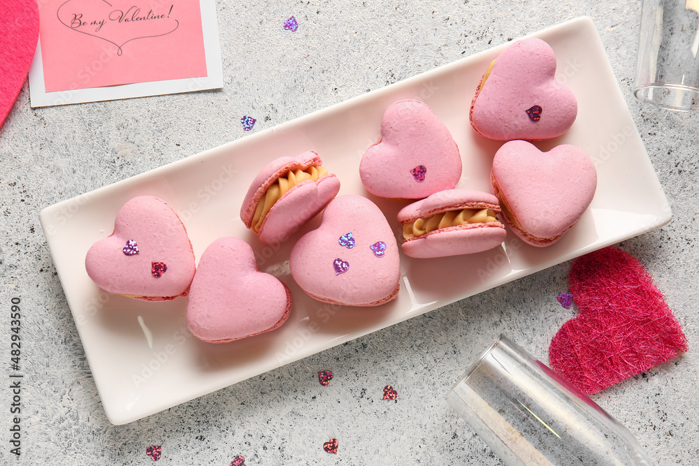 Plate with tasty heart-shaped macaroons on light background