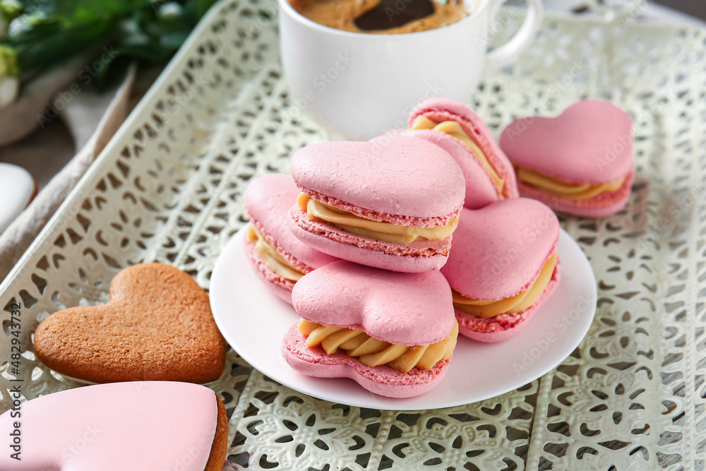 Plate with tasty heart-shaped macaroons on table