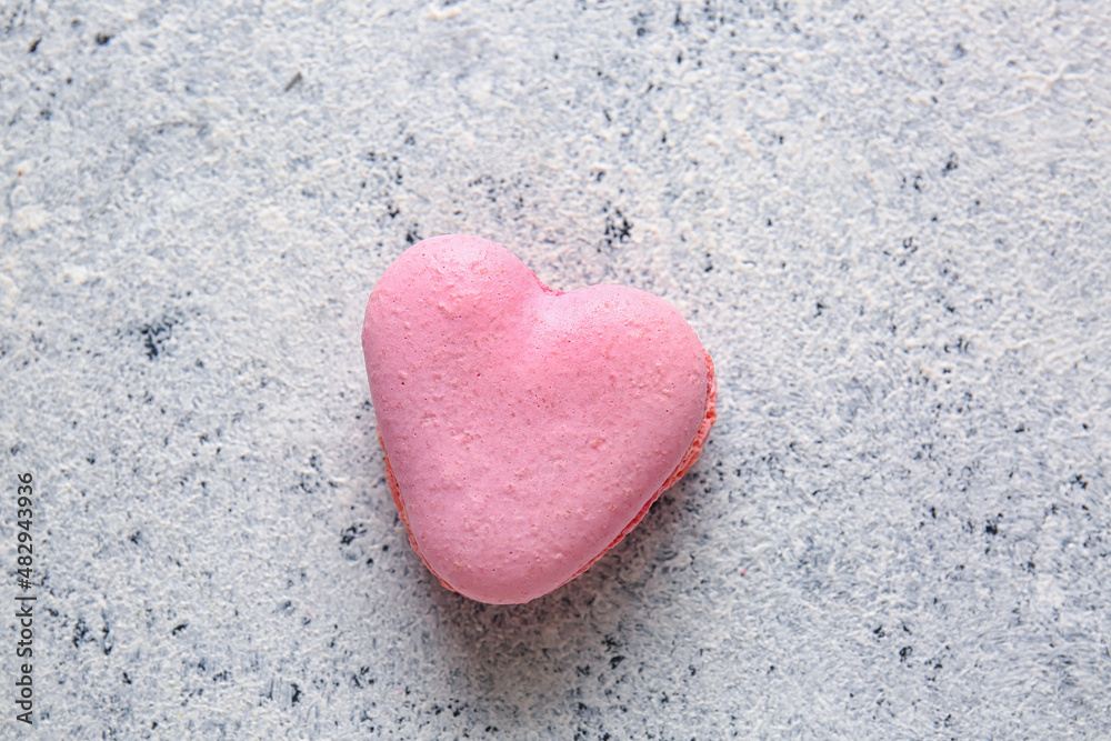 Tasty heart-shaped macaroon on light background