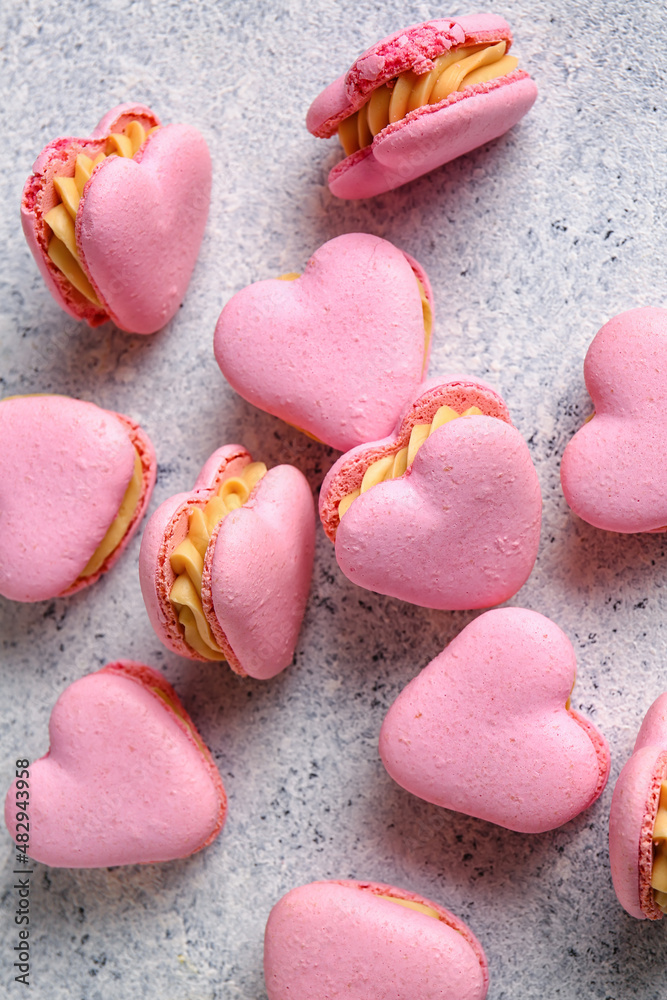 Tasty heart-shaped macaroons on light background