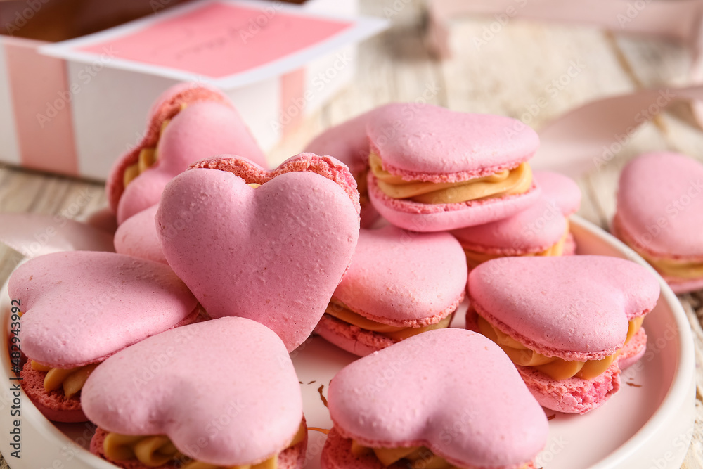 Plate with tasty heart-shaped macaroons on table, closeup