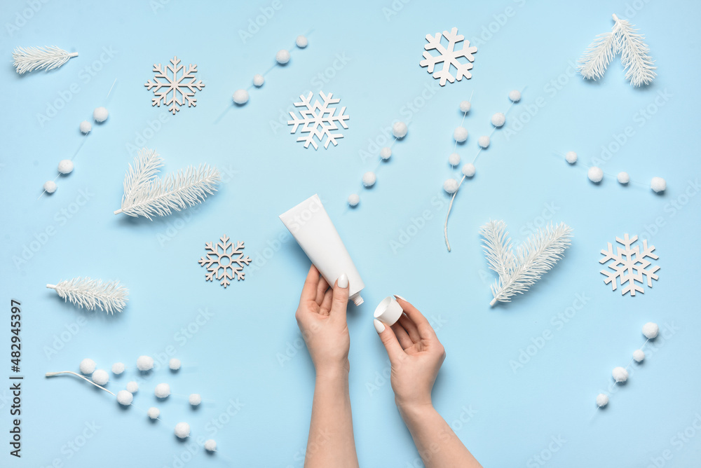 Woman opening tube with cream on color background with winter decor