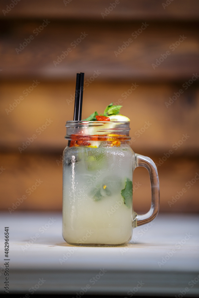 Fresh passion fruit lemonade with crushed ice and lime and straw on table with wood background