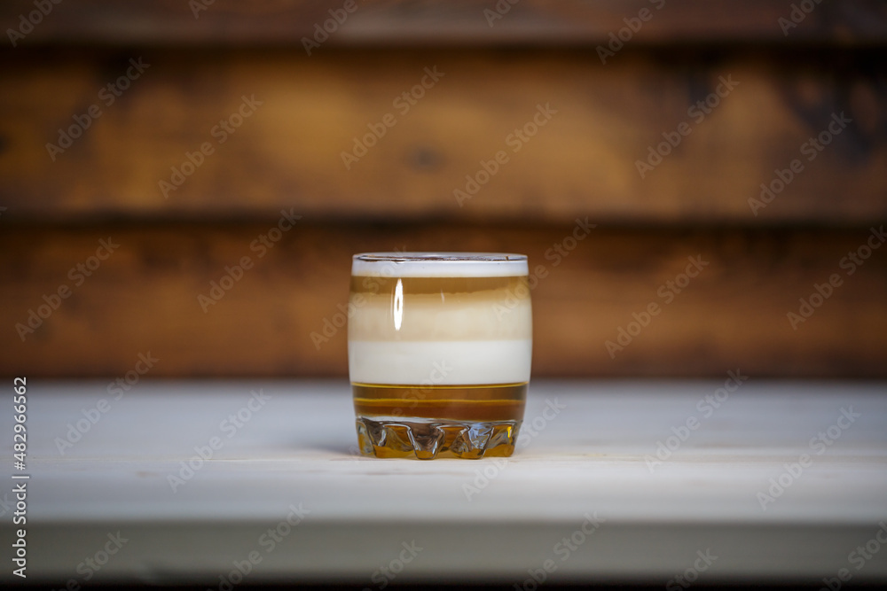 Layered coffee in short glass on table with wood background