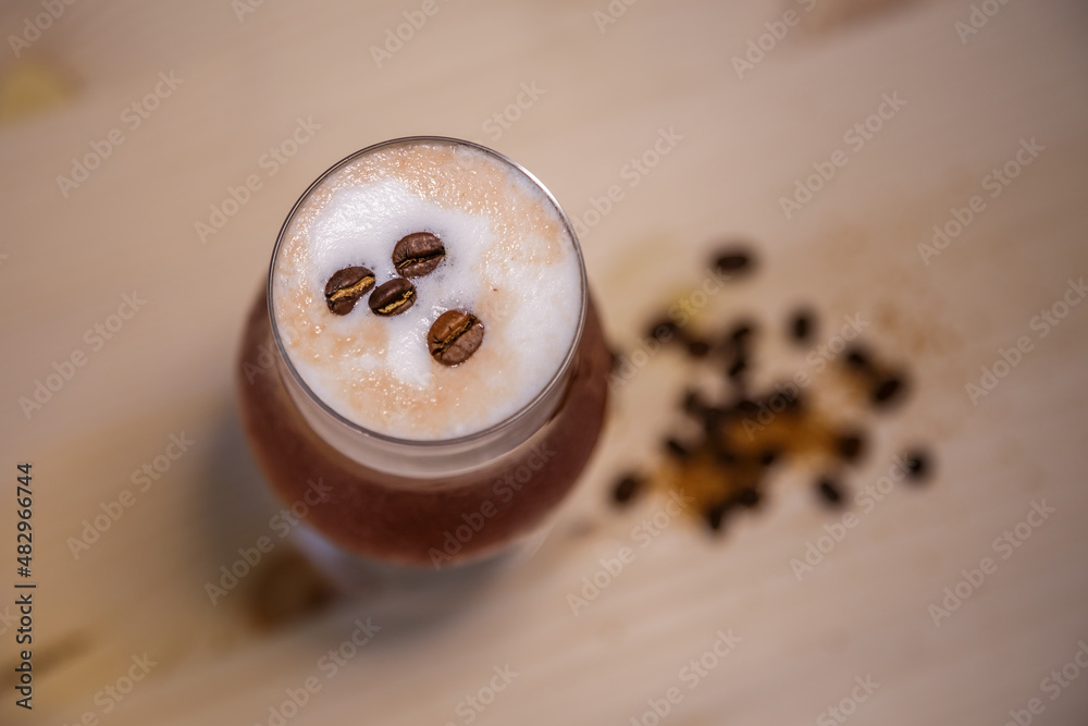 Crushed ice coffee with cinamon in brandy glass from above on table with wood background and coffee 