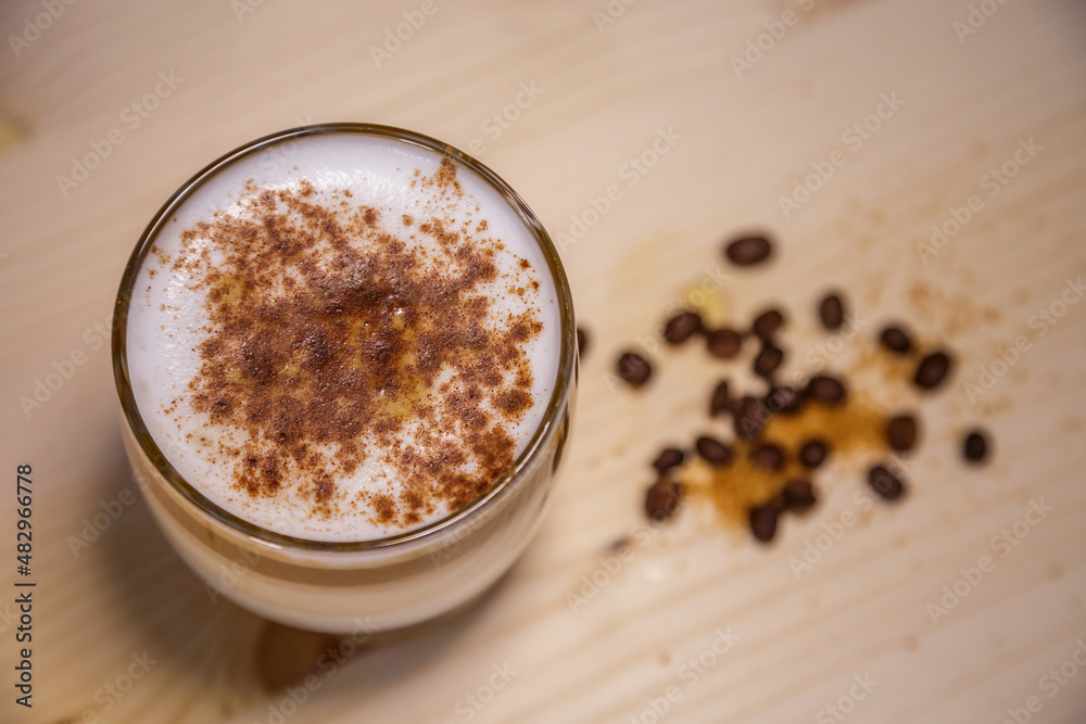 Layered coffee with cinamon in short glass from above on table with wood background and coffee beans