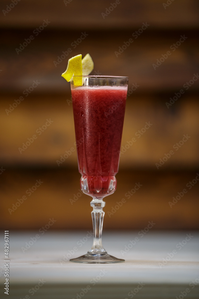 Fresh cold berries cocktail and crushed ice and lemon twist on table with wood background