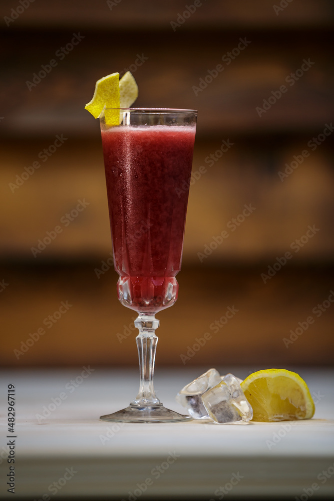 Fresh cold berries cocktail and crushed ice and lemon twist on table with wood background