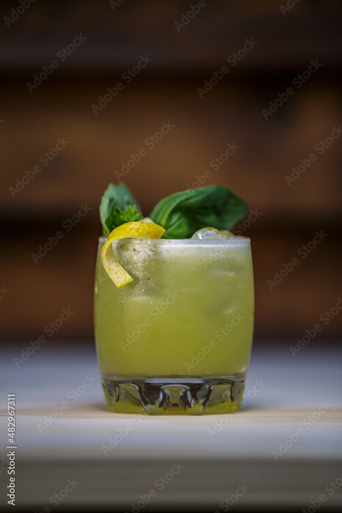 Fresh cold lime smoothie cocktail with mint and crushed ice and lemon twist to garnish on table with