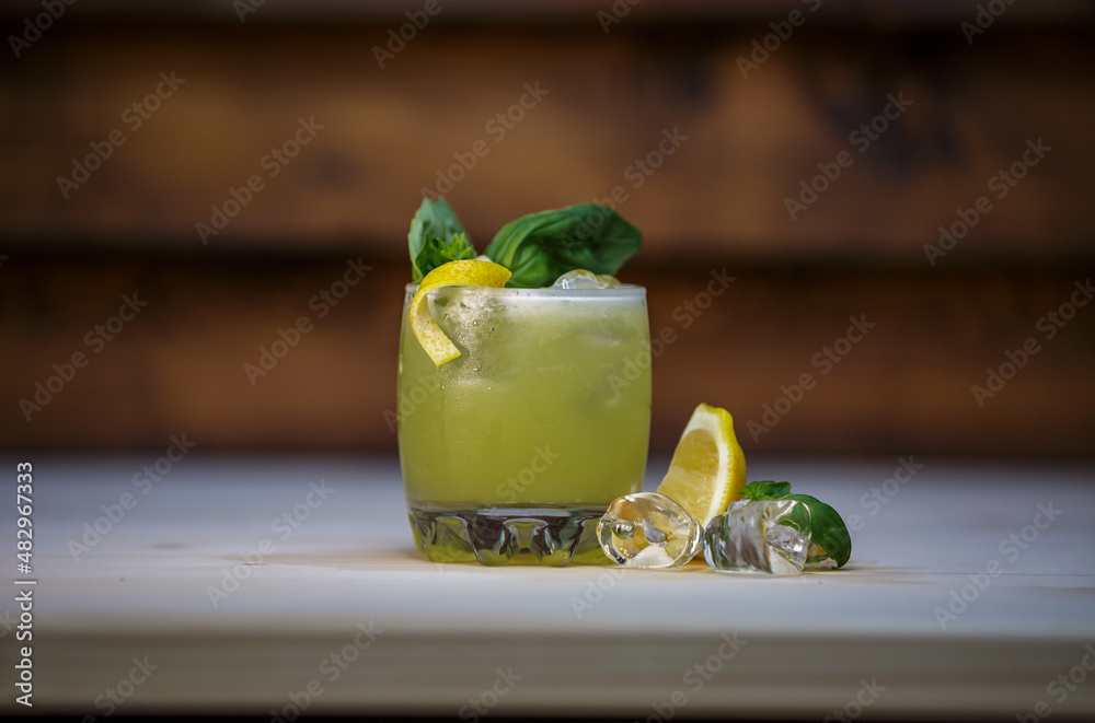 Fresh cold lime smoothie cocktail with mint and crushed ice and lemon twist to garnish on table with