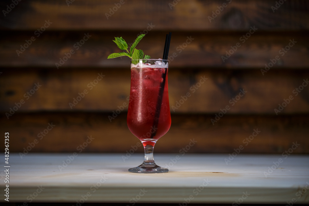 Fresh cold pomegranate cocktail with mint and crushed ice on table with wood background