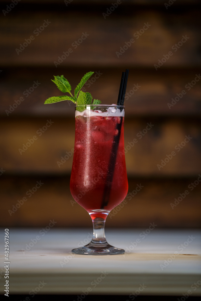 Fresh cold pomegranate cocktail with mint and crushed ice on table with wood background