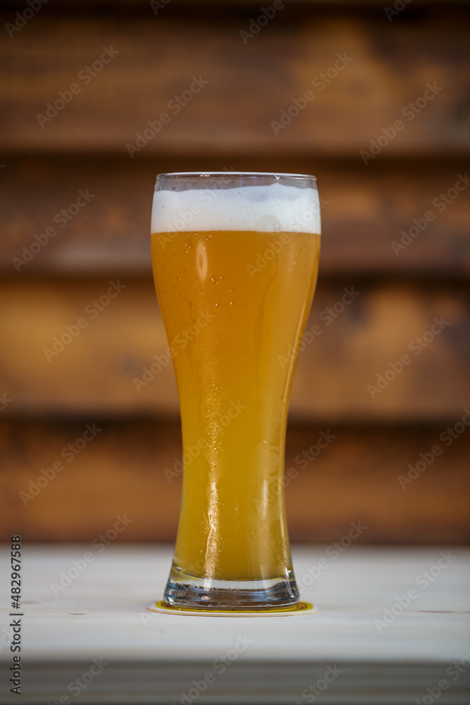 Fresh tall grass of beer on table with wood background