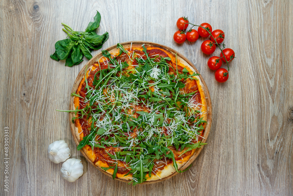 pizza with ham, arugula, tomato sauce and shredded mozzarella