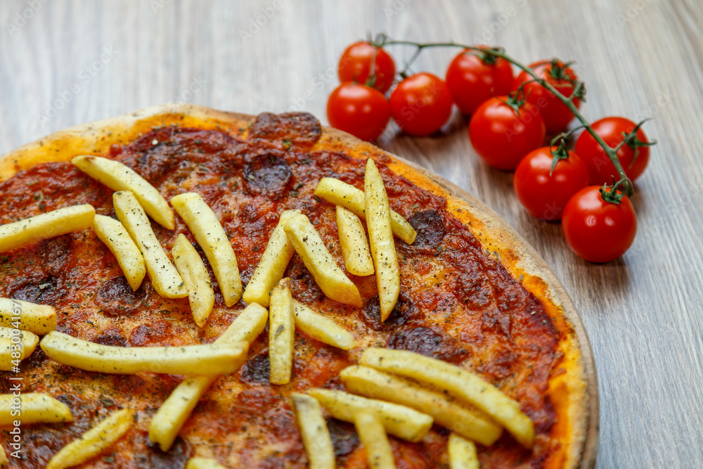 pizza with hot sausage and french fries on tomato sauce