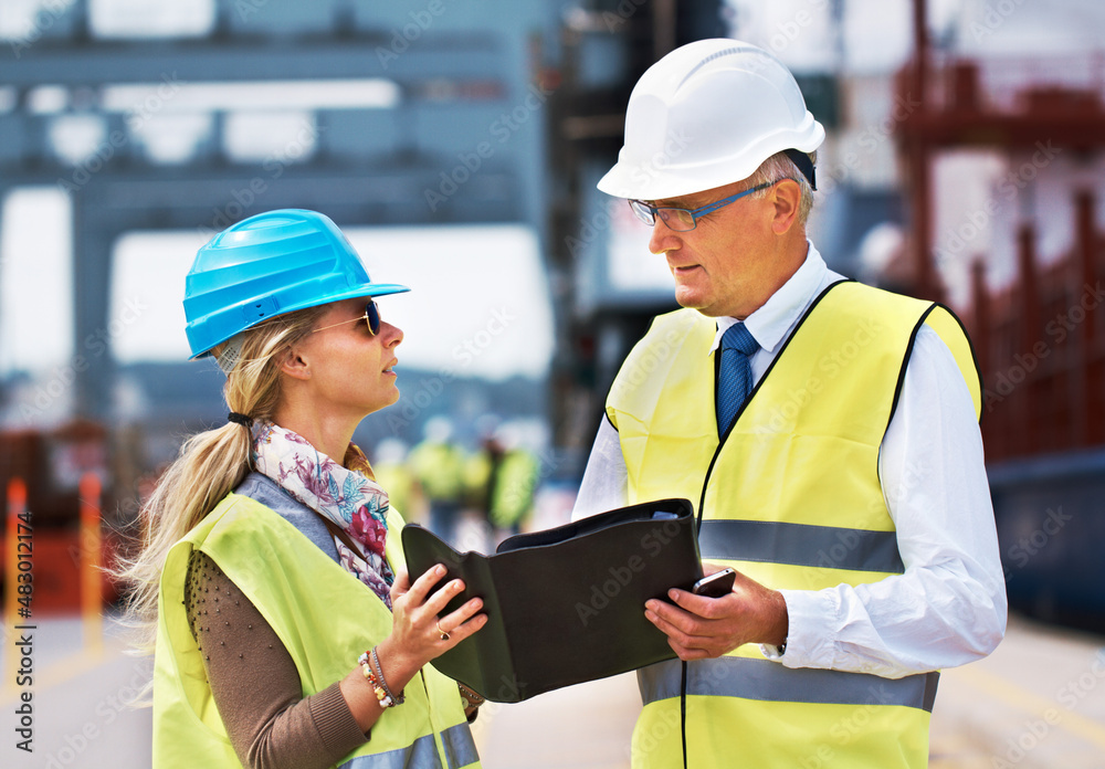 Working together creates success. Two work colleagues standing in a harbor and discussing work...