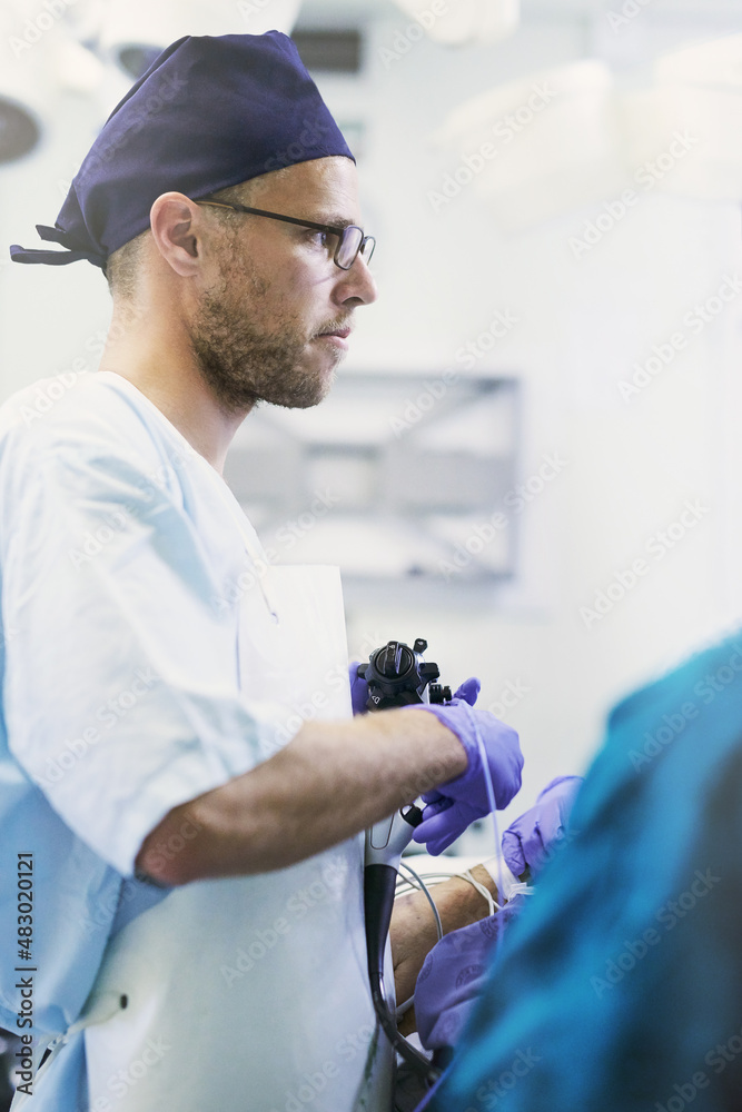 Life saving is what he does. Shot of a young surgeon performing surgery on a patient in an operating