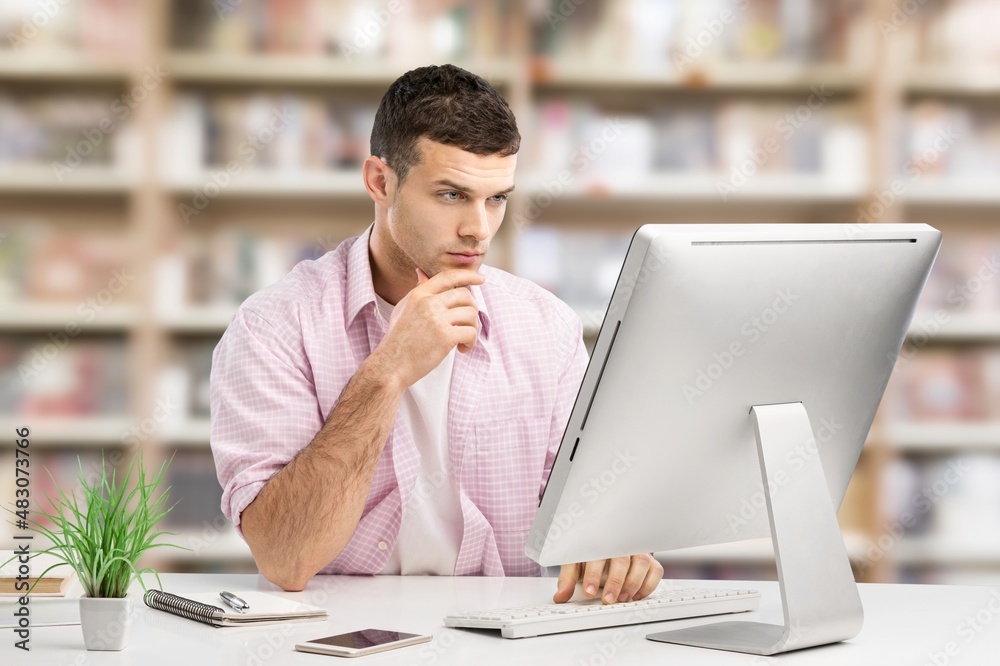 Young male student watching education webinar using laptop writing notes doing research on the inter