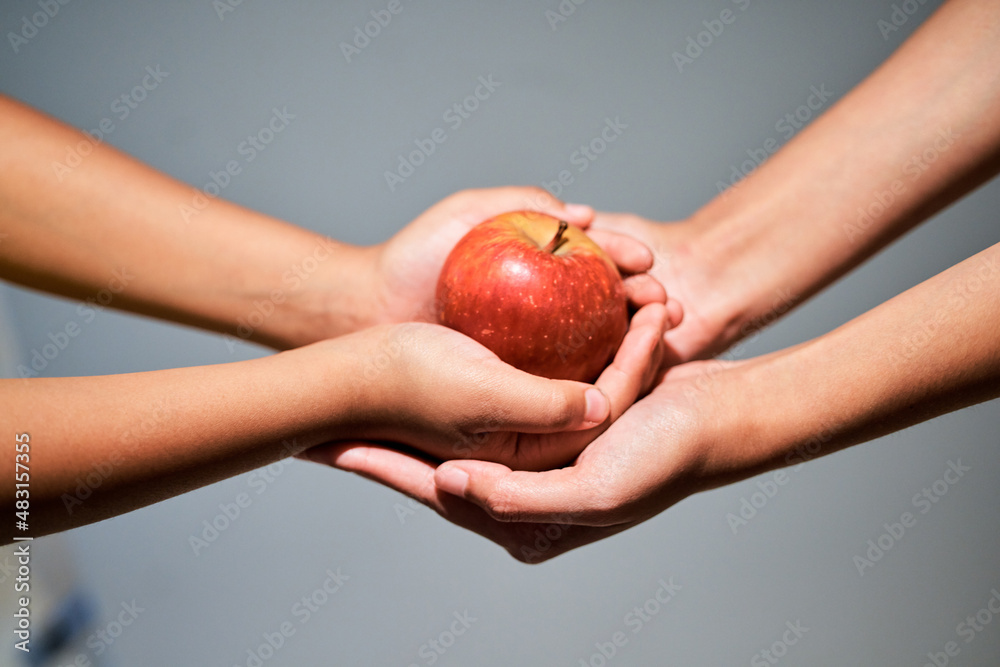 An apple a day.... Studio shot of an unrecognizable woman giving a child an apple.