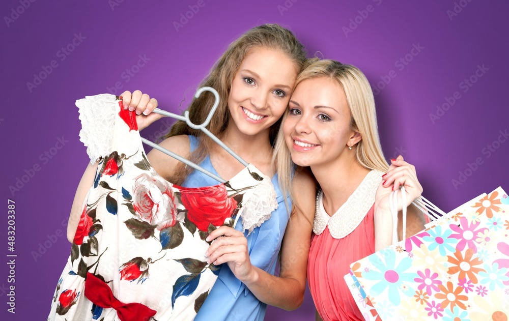 Two happy women friends shoppers holding shopping bags. Retail fashion sale offers, mall discounts c