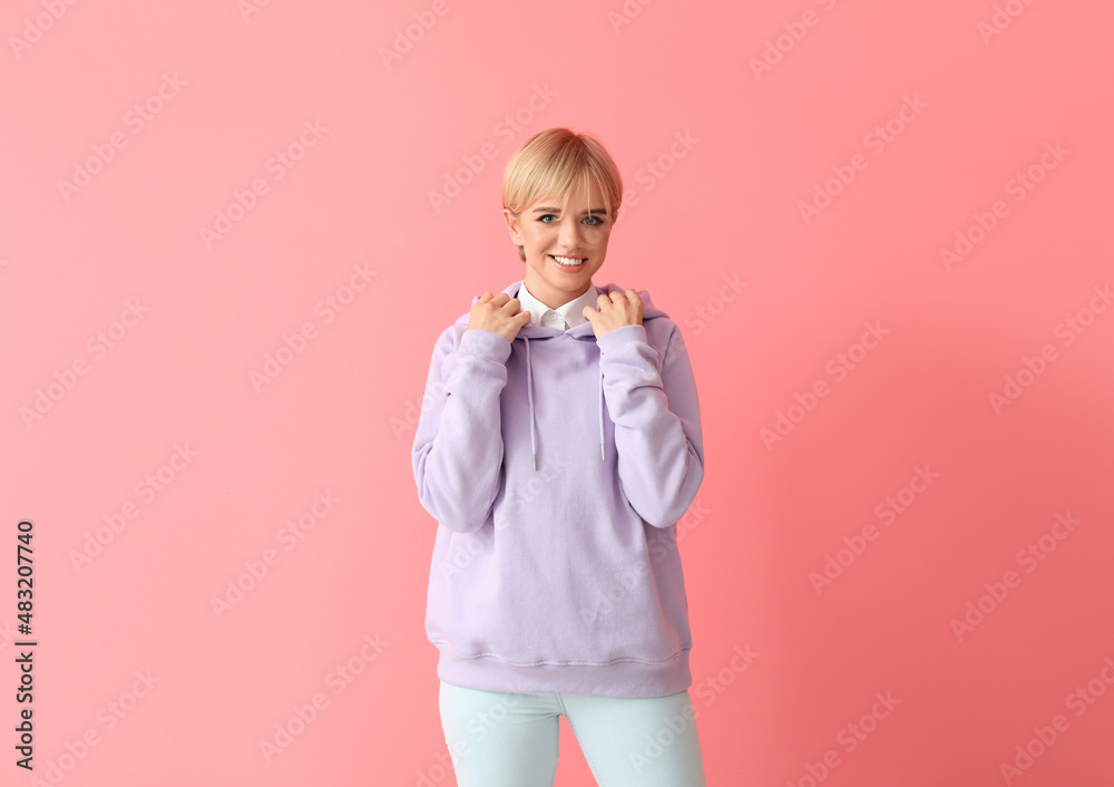 Beautiful young woman in stylish hoodie on color background