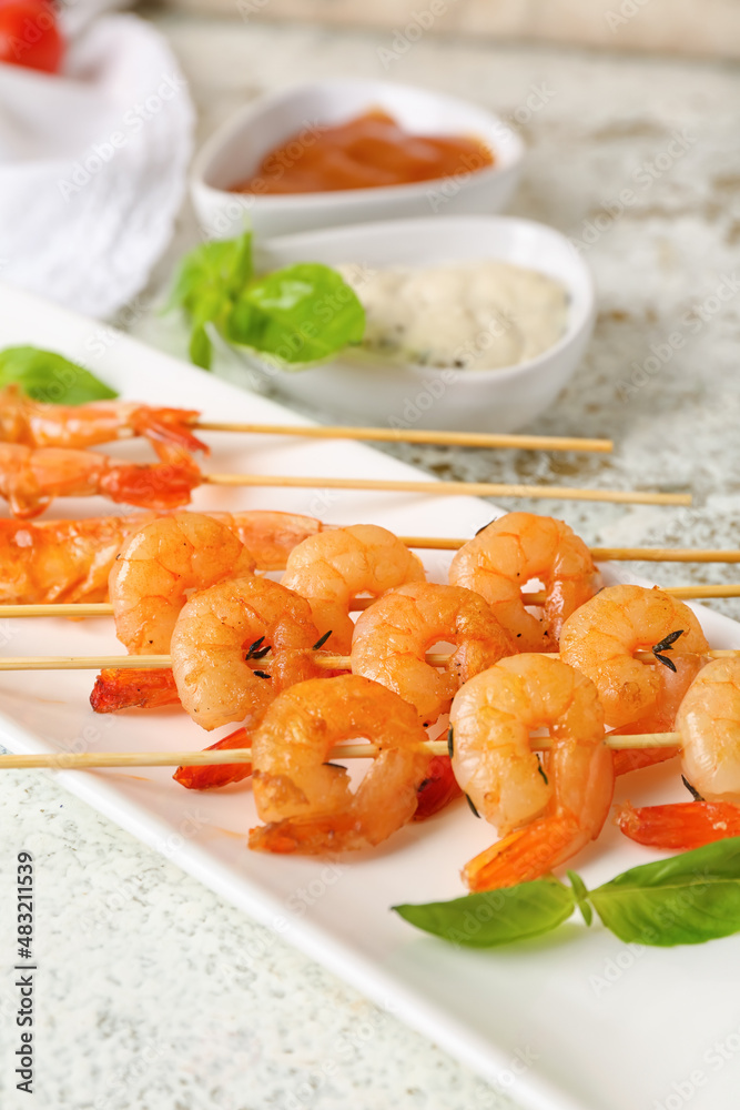 Plate with tasty grilled shrimp skewers on light background