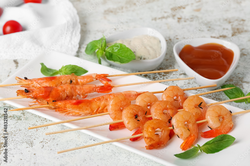 Plate with tasty grilled shrimp skewers and sauces on light background