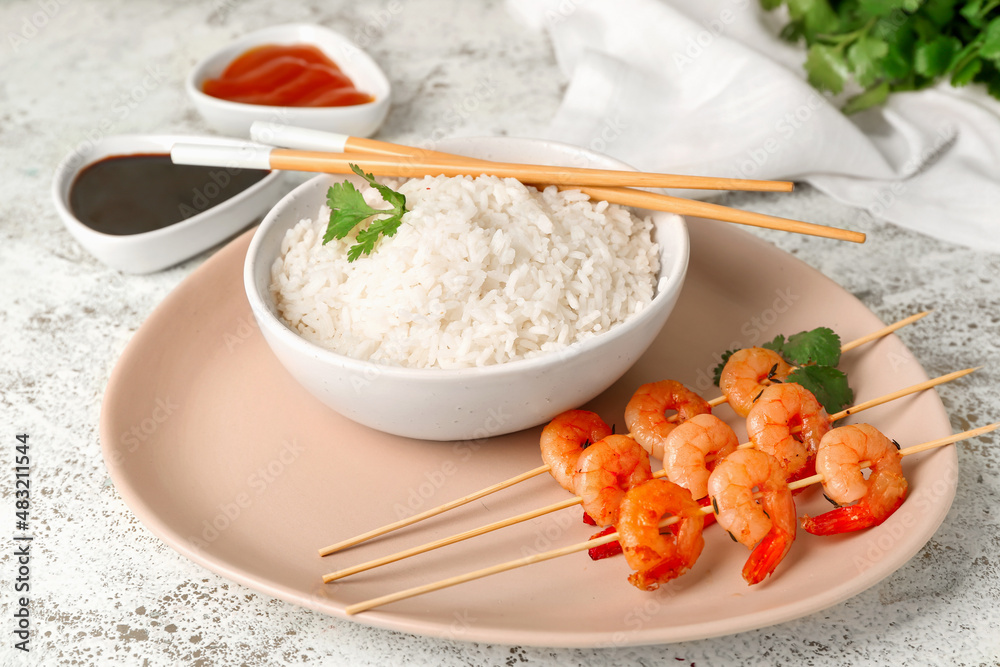 Plate with tasty grilled shrimp skewers, rice and sauce on light background