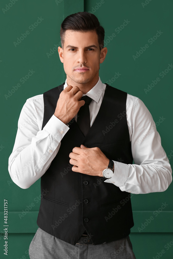 Gentleman in stylish formal clothes adjusting collar on color background