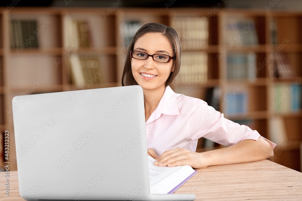 A female professor used laptop while doing a research at university library.