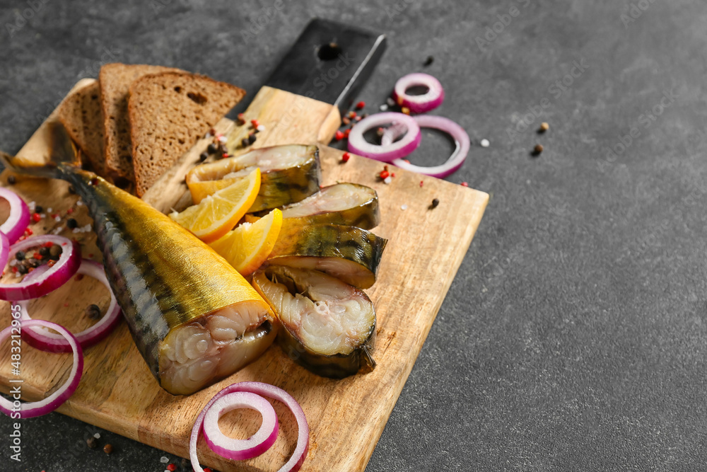 Wooden board cut smoked mackerel fish and bread on black background