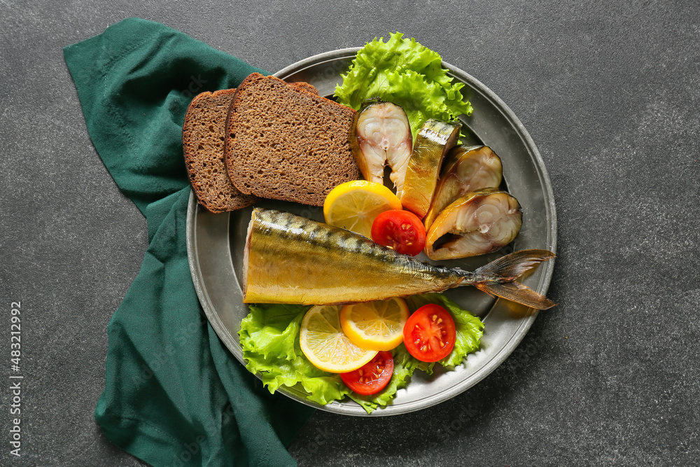 Plate with cut smoked mackerel fish and bread on black background