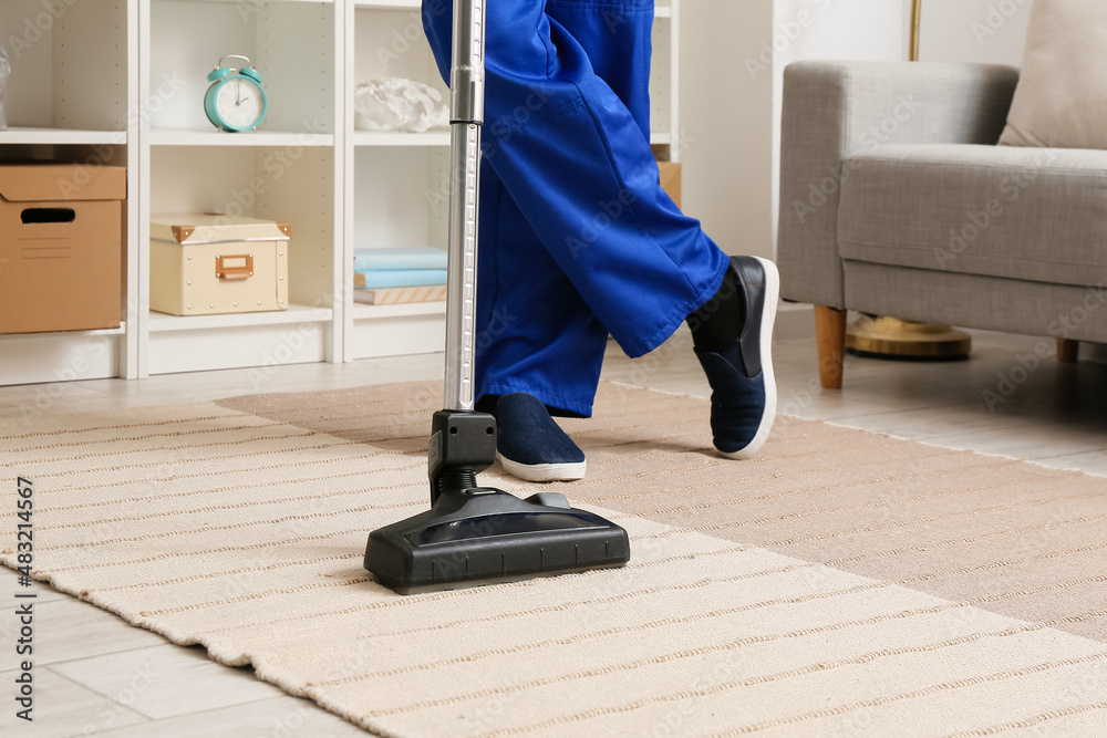 Male worker cleaning stylish carpet in room