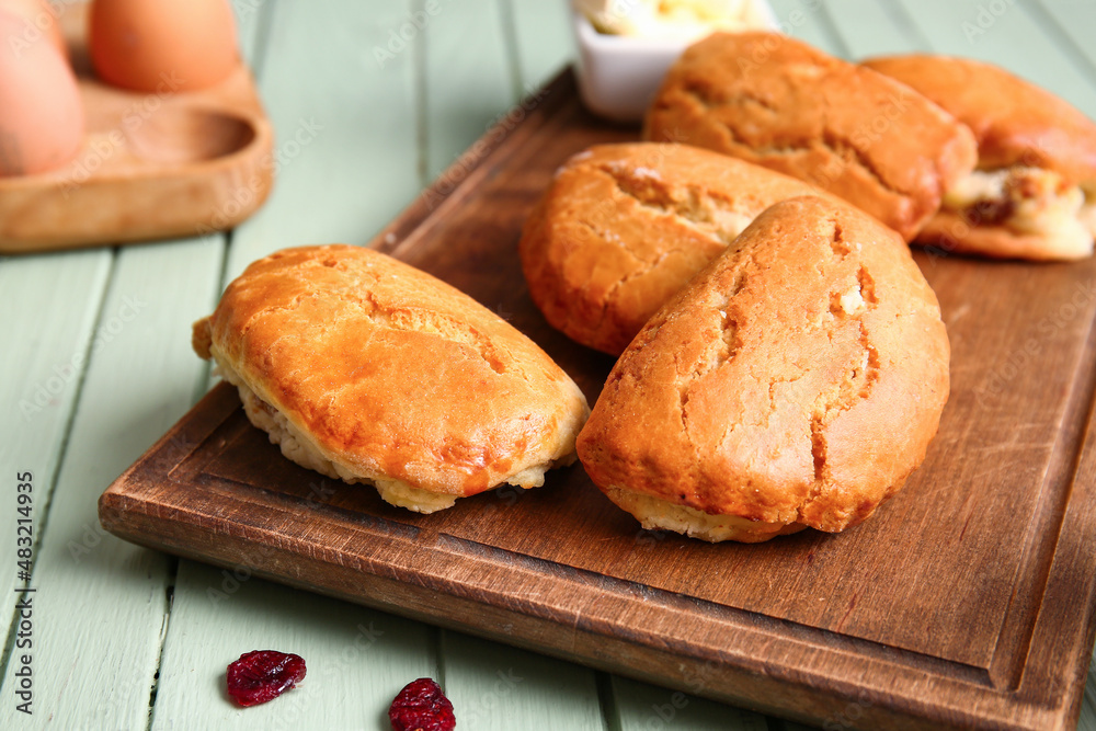 Board of tasty sochniki with cottage cheese on green wooden background, closeup