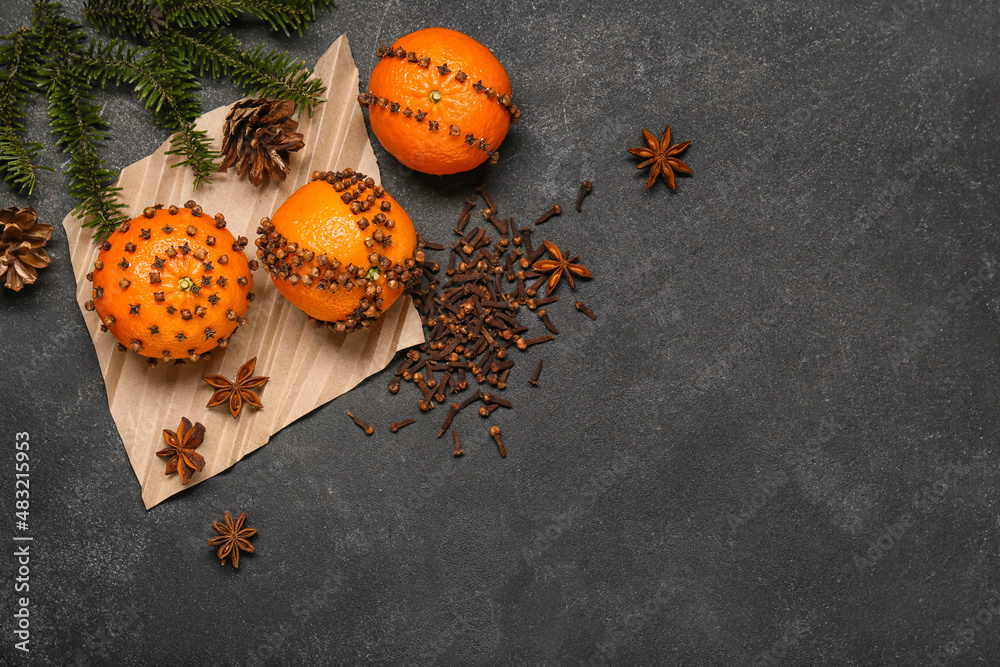 Handmade Christmas decoration made of tangerines with cloves and fir branch on dark background