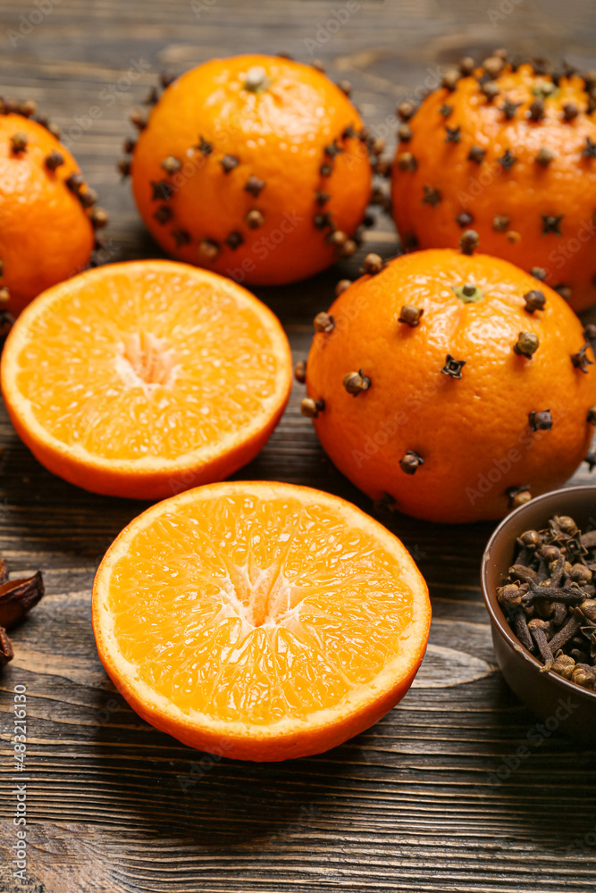 Handmade Christmas decoration made of tangerines with cloves on wooden background, closeup