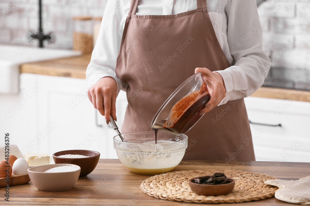 Woman preparing chocolate brownie at kitchen table, closeup