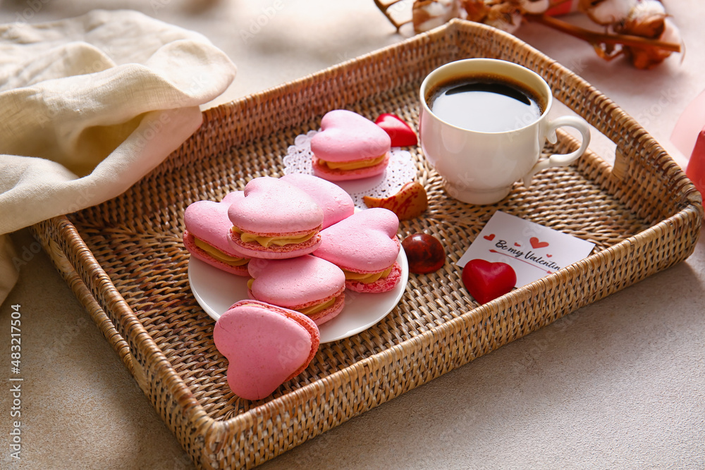 Tray with tasty heart-shaped macaroons and cup of coffee on light background