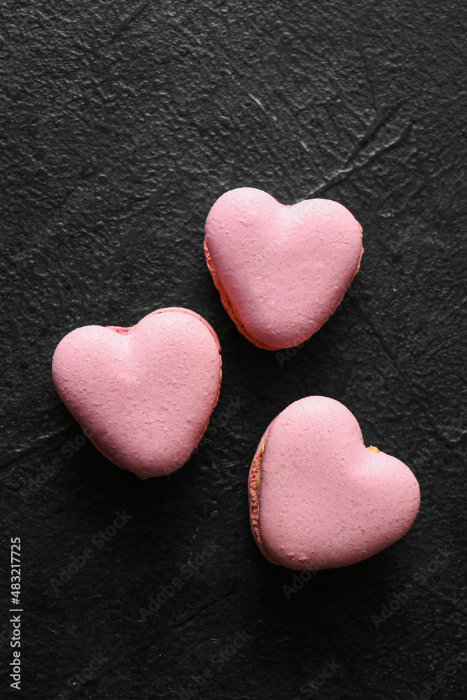 Tasty heart-shaped macaroons on black background